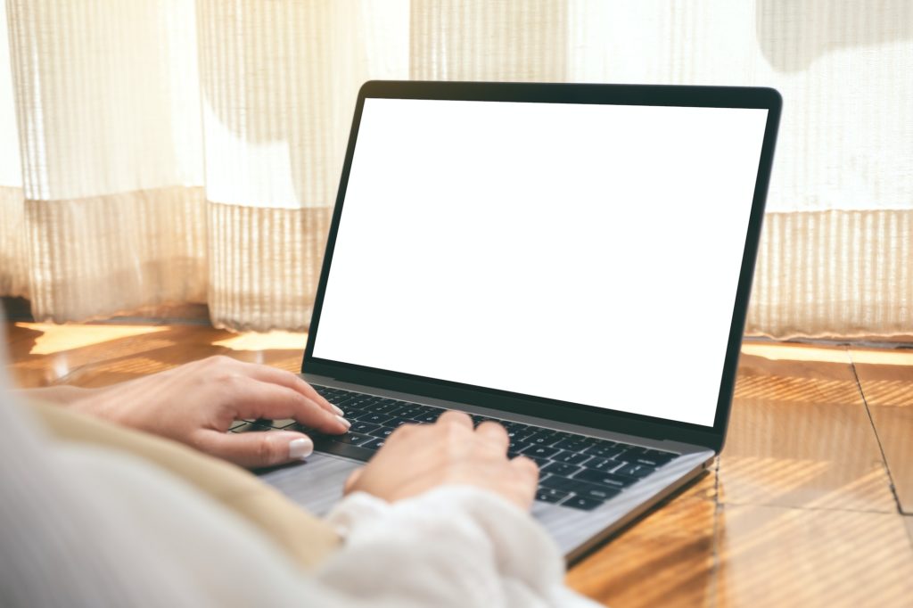 a woman using laptop computer with blank white desktop screen